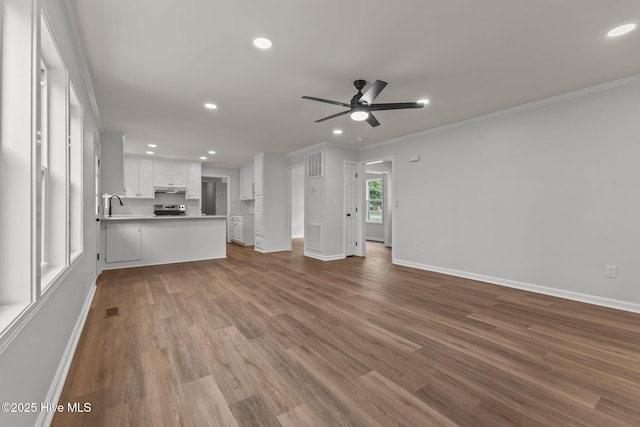 unfurnished living room with light wood-type flooring, ceiling fan, ornamental molding, and sink