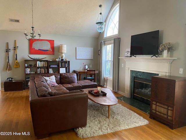 living room with a fireplace, hardwood / wood-style floors, a textured ceiling, and a chandelier