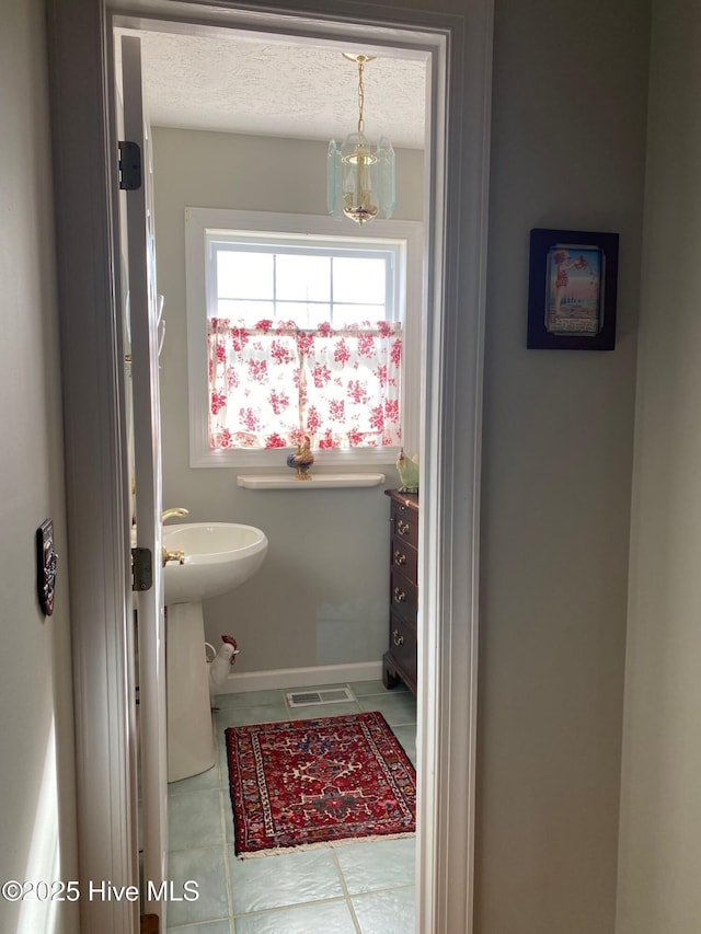 bathroom with a chandelier, a textured ceiling, and tile patterned flooring