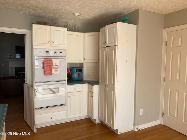 kitchen with white cabinets, a textured ceiling, and white double oven