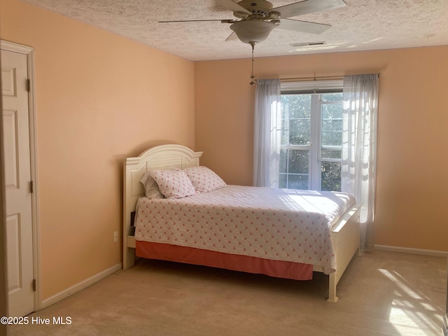 bedroom with a textured ceiling, light colored carpet, and ceiling fan