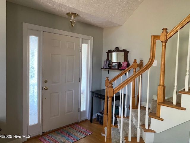 entryway with hardwood / wood-style floors and a textured ceiling