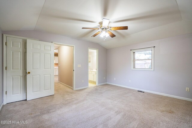 unfurnished bedroom featuring ensuite bathroom, vaulted ceiling, ceiling fan, and light colored carpet