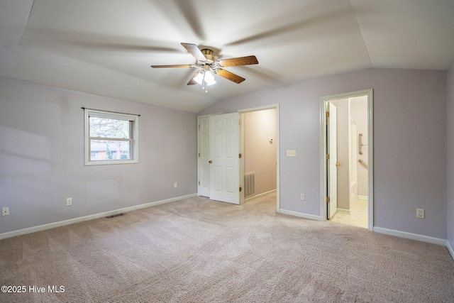 unfurnished bedroom with light carpet, ensuite bath, ceiling fan, and lofted ceiling