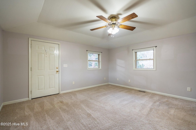 unfurnished room with ceiling fan, light colored carpet, and a tray ceiling