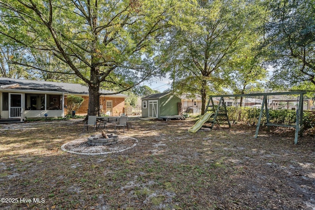 view of yard with a playground, a storage unit, and an outdoor fire pit