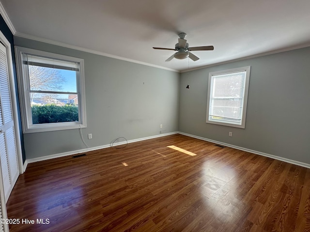 unfurnished room with plenty of natural light, ceiling fan, dark wood-type flooring, and crown molding