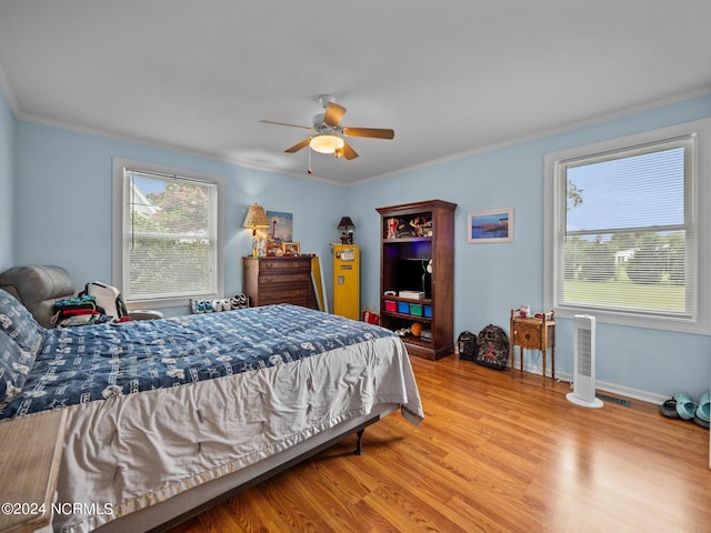 bedroom featuring light wood-type flooring, ceiling fan, and crown molding