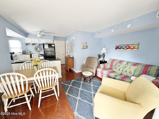 living room featuring dark wood-type flooring, visible vents, and baseboards