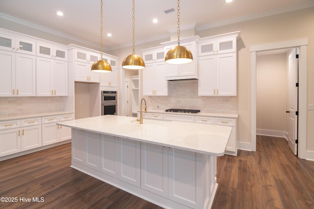 kitchen featuring white cabinets, crown molding, an island with sink, tasteful backsplash, and stainless steel appliances