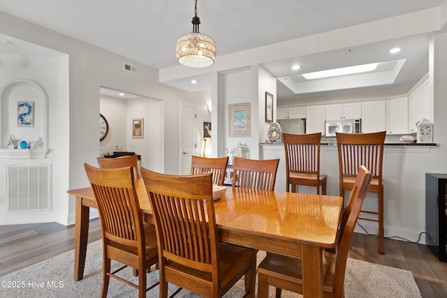 dining area featuring a raised ceiling, dark wood-type flooring, and a chandelier