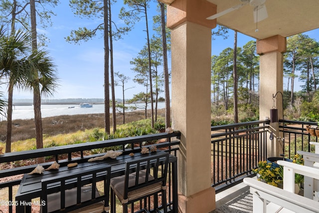 balcony with ceiling fan and a water view