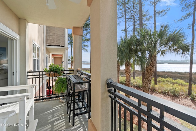 balcony with ceiling fan and a water view