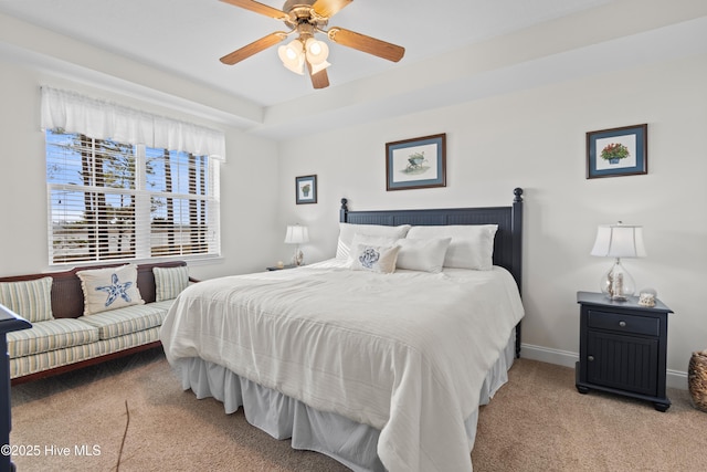 carpeted bedroom with a tray ceiling and ceiling fan