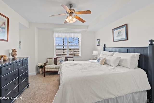 carpeted bedroom featuring a raised ceiling and ceiling fan