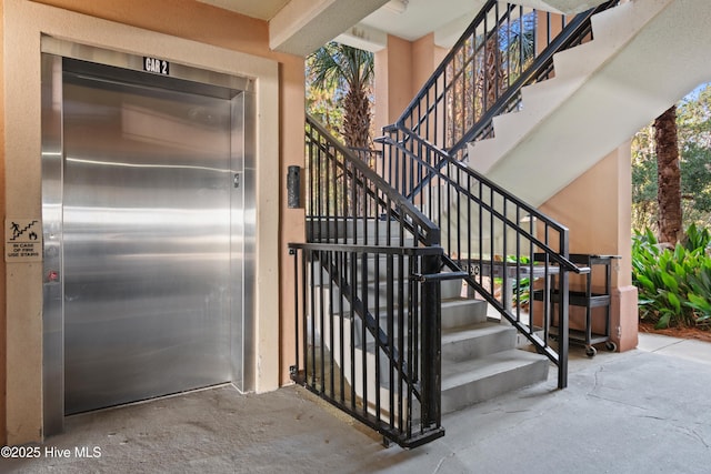 stairway featuring concrete flooring and elevator