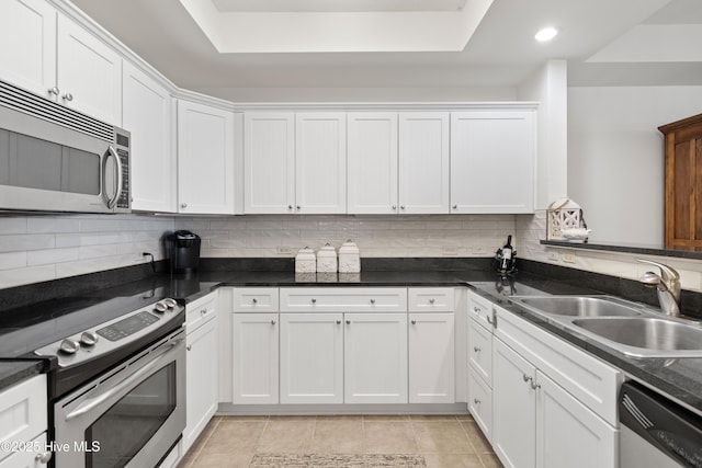 kitchen featuring sink, dark stone countertops, decorative backsplash, white cabinets, and appliances with stainless steel finishes