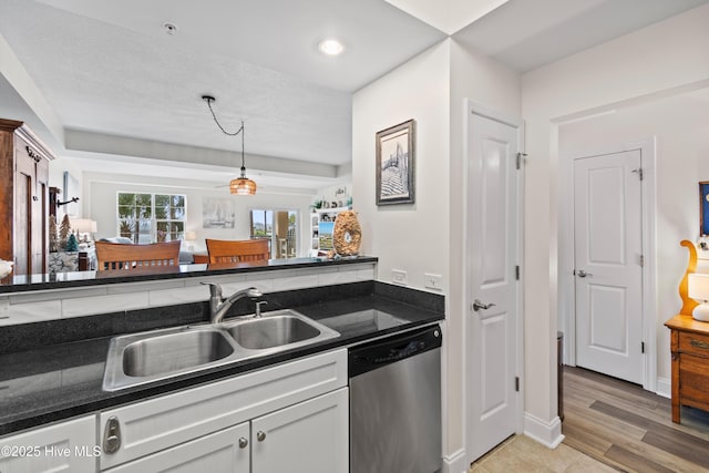 kitchen featuring stainless steel dishwasher, sink, decorative light fixtures, light hardwood / wood-style flooring, and white cabinets