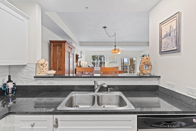 kitchen with decorative backsplash, dishwashing machine, sink, white cabinets, and hanging light fixtures