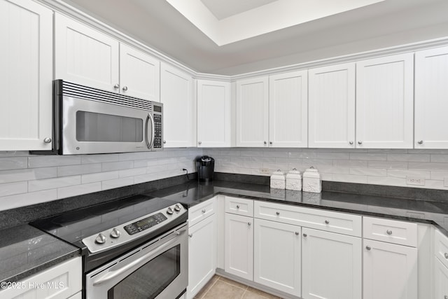 kitchen featuring dark stone counters, white cabinets, and stainless steel appliances