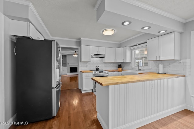 kitchen with decorative backsplash, butcher block countertops, white cabinets, and stainless steel appliances