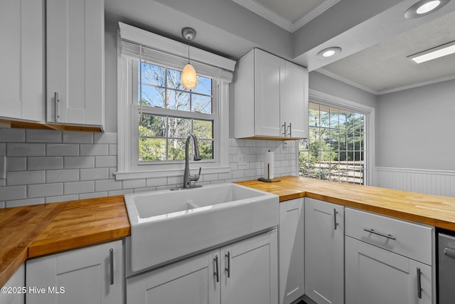 kitchen featuring tasteful backsplash, butcher block countertops, sink, white cabinetry, and hanging light fixtures