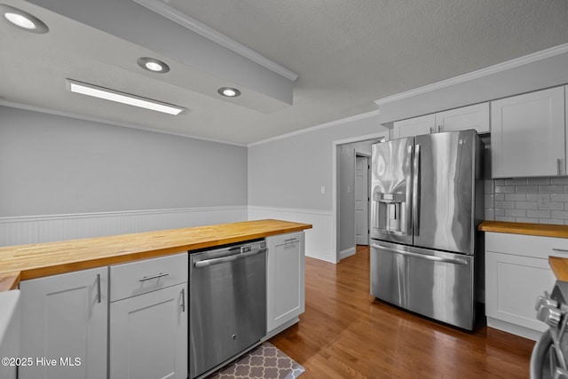 kitchen with stainless steel appliances, white cabinetry, and butcher block countertops