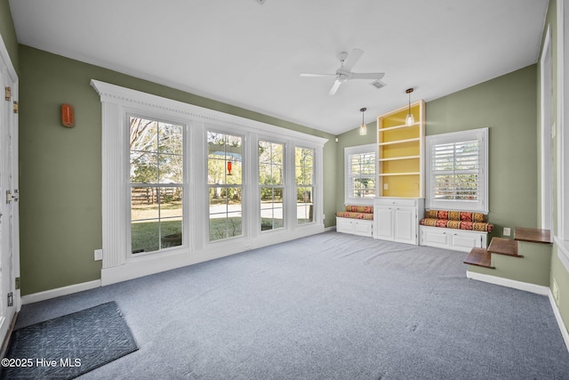 unfurnished living room with lofted ceiling, ceiling fan, a wealth of natural light, and carpet flooring