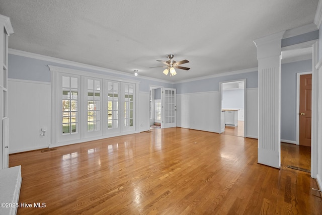 unfurnished living room featuring ceiling fan, hardwood / wood-style floors, ornamental molding, and ornate columns