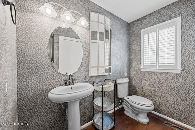 bathroom with toilet, wood-type flooring, and sink