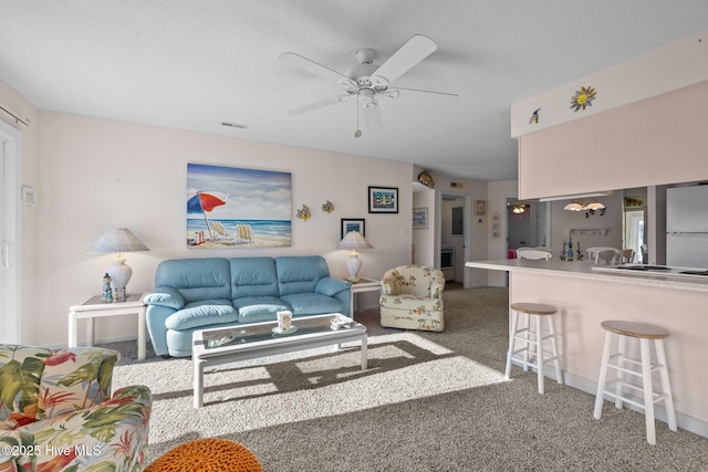 carpeted living room with ceiling fan and a textured ceiling