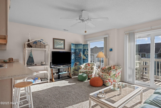 carpeted living room featuring a textured ceiling, a wealth of natural light, and ceiling fan