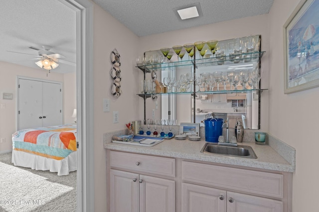 bar featuring ceiling fan, sink, carpet, and a textured ceiling