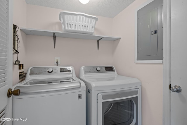 washroom with electric panel, washer and dryer, and a textured ceiling