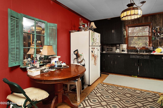 kitchen featuring pendant lighting, sink, white fridge, crown molding, and light hardwood / wood-style flooring