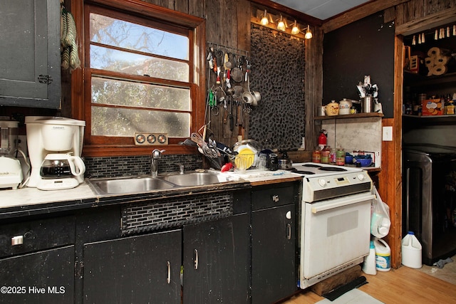 kitchen with electric stove, decorative backsplash, sink, and light hardwood / wood-style flooring