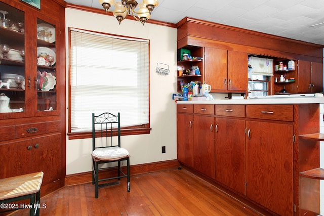 kitchen featuring an inviting chandelier, ornamental molding, and light hardwood / wood-style floors