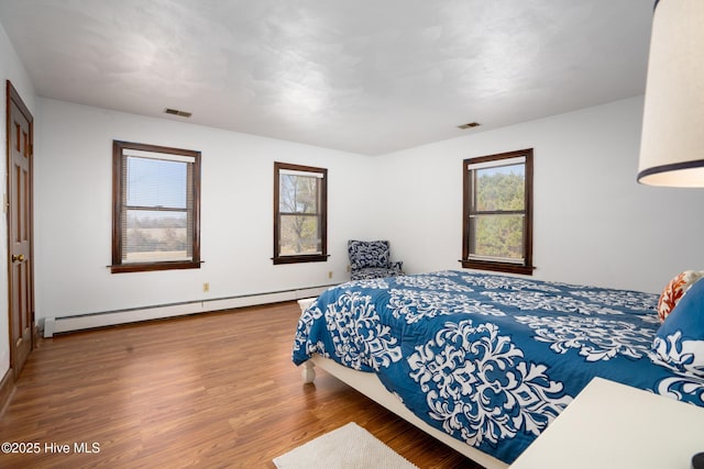 bedroom featuring hardwood / wood-style floors and a baseboard radiator