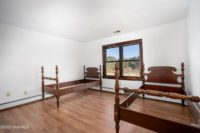 bedroom featuring wood-type flooring and a baseboard radiator