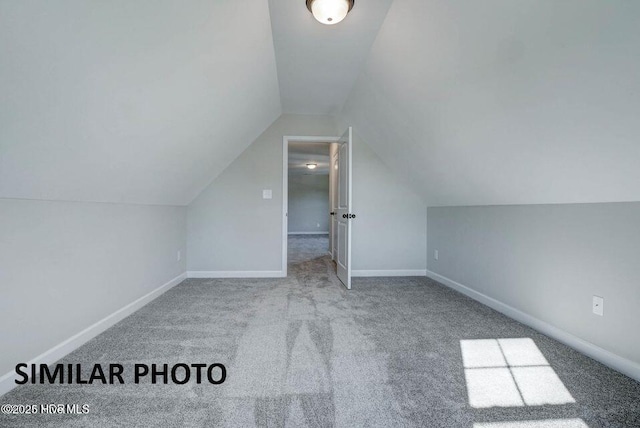 additional living space featuring vaulted ceiling and light colored carpet