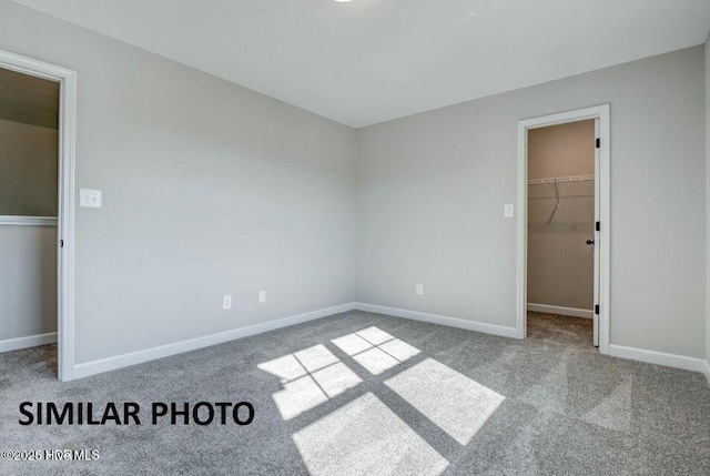 unfurnished bedroom featuring light carpet, a walk in closet, and a closet