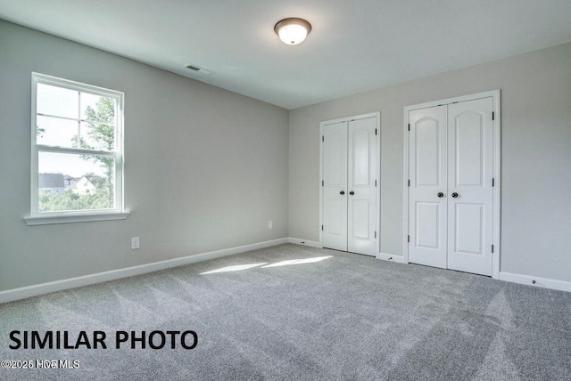 unfurnished bedroom with multiple closets and carpet