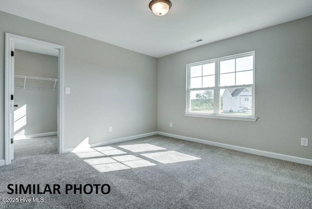 unfurnished bedroom featuring light carpet, a spacious closet, and a closet