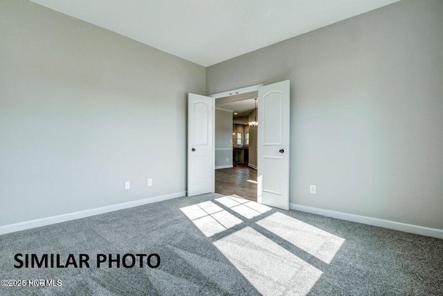 carpeted empty room with a chandelier