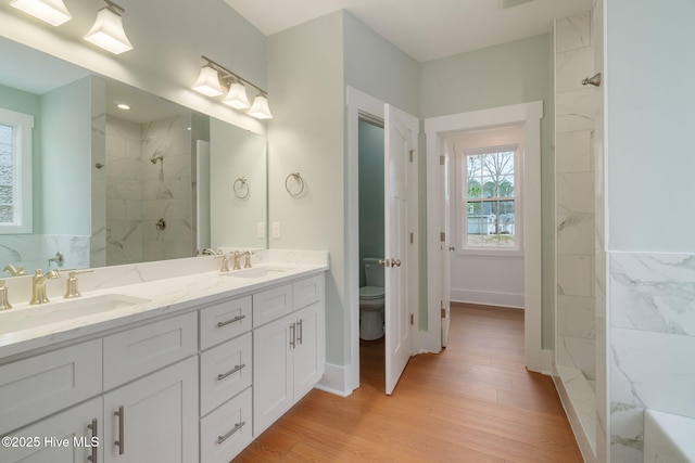 bathroom with vanity, hardwood / wood-style flooring, toilet, and tiled shower