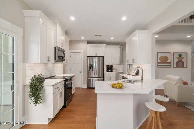 kitchen featuring white cabinetry, appliances with stainless steel finishes, sink, and hardwood / wood-style flooring