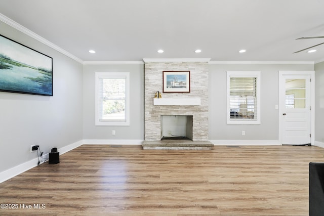 unfurnished living room featuring light hardwood / wood-style flooring, a stone fireplace, ceiling fan, and crown molding