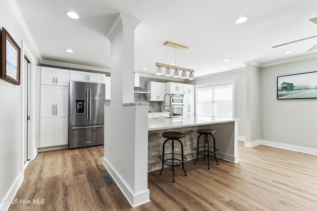 kitchen featuring a kitchen breakfast bar, white cabinetry, kitchen peninsula, and appliances with stainless steel finishes