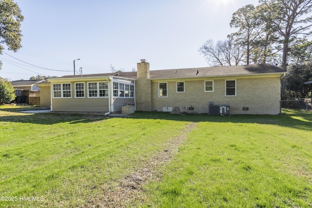 rear view of house featuring cooling unit and a yard