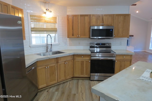 kitchen featuring pendant lighting, backsplash, sink, light hardwood / wood-style flooring, and stainless steel appliances